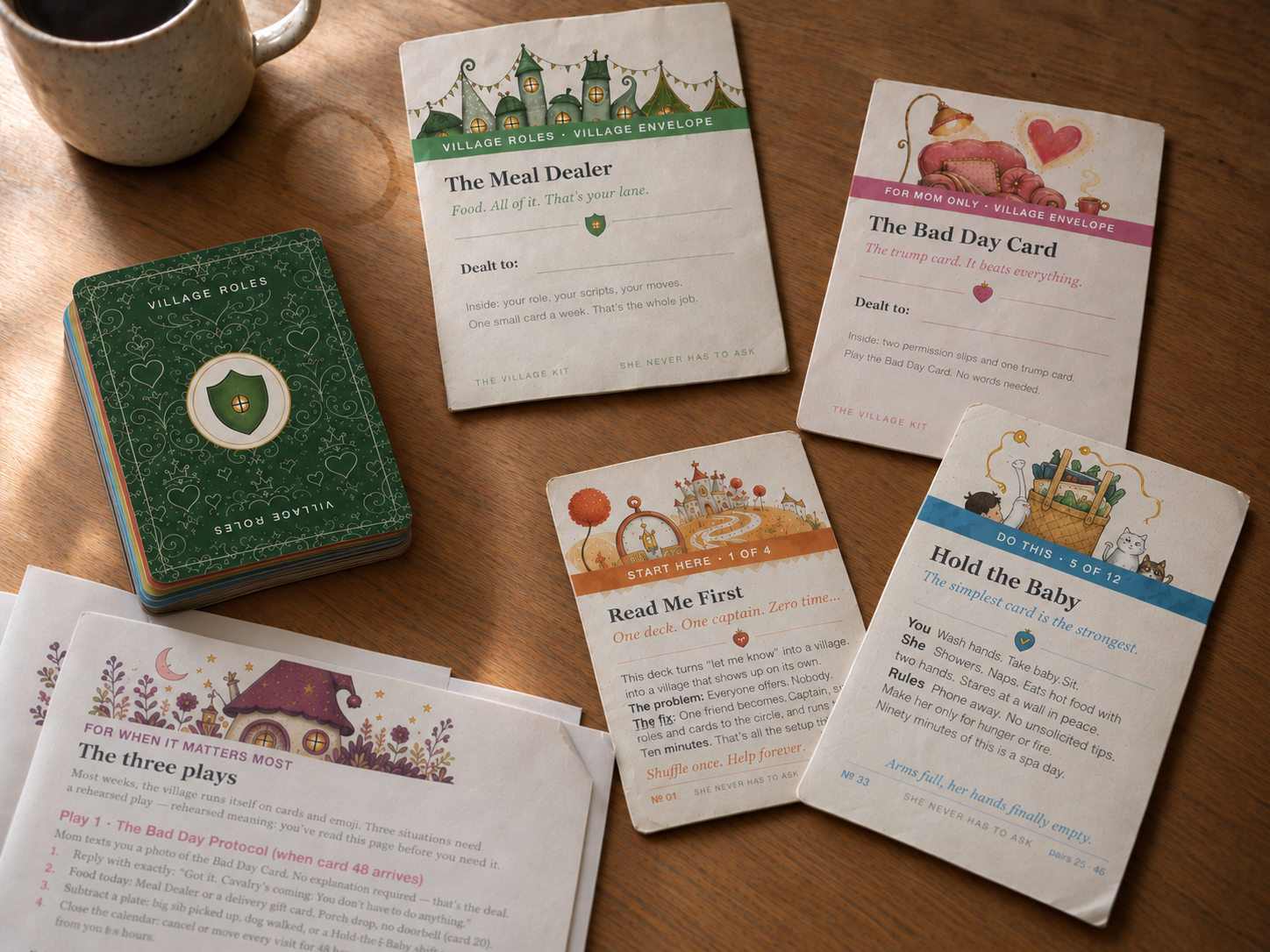 The Village Kit laid out on a table — cards, role envelopes and the printed Playbook pages