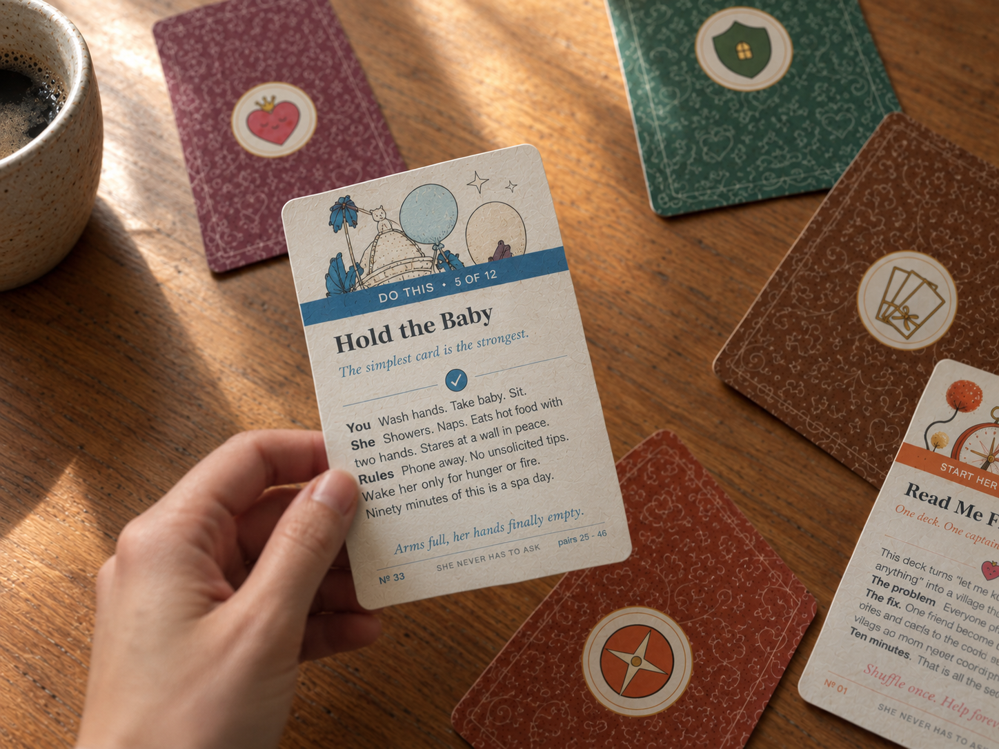 A hand holding a Village Kit card while the rest of the deck lies on a wooden table